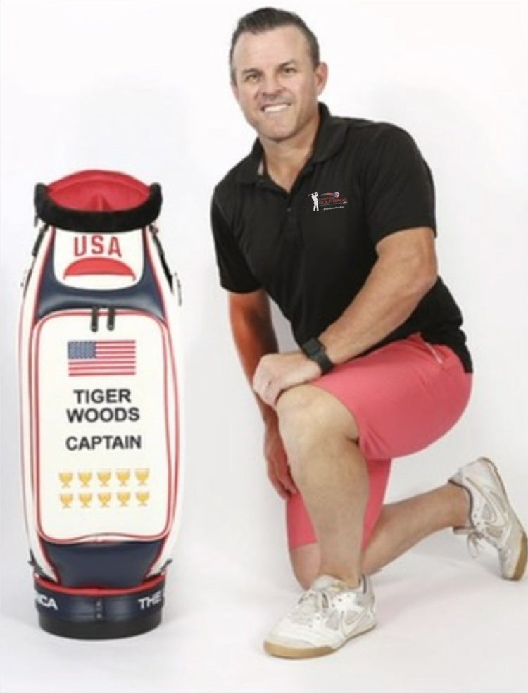 Founder Travis Mclean in a Custom Golf Bags USA shirt, kneeling beside the Tiger Woods USA captain's bag from the 2019 Presidents Cup